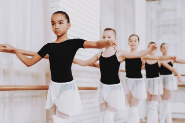 Genç kızların kapalı grubunun bale eğitimi. Klasik bale. Kız balerin Tutu. Kapalı eğitim. Şirin dansçılar. Performans salonunda. Pratik dans. Kızlar beyaz elbiseler.