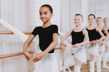 Genç kızların kapalı grubunun bale eğitimi. Klasik bale. Kız balerin Tutu. Kapalı eğitim. Şirin dansçılar. Performans salonunda. Pratik dans. Kızlar beyaz elbiseler.