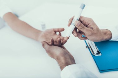 Çocuğun parmak gelen doktor alarak kan örneği. Diyabet kavramı. Kan şekeri. Sağlık kavramı. Üniformalı genç adam. Beyaz önlük. Tıbbi malzeme. Çocuk Kliniği. Elinde şeker ölçüm.