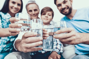 Evde gözlük gülümseyen aile içme suyu. Baba ve oğul. Gülümseyen insanlar. Ebeveynlik kavramı. Evde aile. Mutlu bir aile. Bir bardak su. Genç kadın. Aile Yemek odasında.