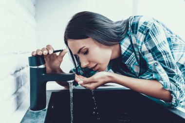Young Woman in Shirt Drinking Water in Kitchen. Healthcare Concept. Fresh Water. Young Woman. Woman in Shirt. Girl in Kitcken. Healthy Drink Concept. Tap in Kitchen. Woman at Home. clipart