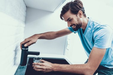 Man in Shirt Drinking Water in Kitchen at Home. Healthcare Concept. Fresh Water. Man in Shirt. Ma in Kitcken. Healthy Drink Concept. Tap in Kitchen. Man at Home. Fresh Water. Thirsty Man. clipart