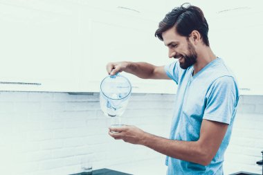 Evde erkek gömlek içme suyu mutfakta. Sağlık kavramı. Tatlı su. T-shirt adam. Ma Kitcken. Sağlıklı içecek konsepti. Adam evde. Tatlı su. Susamış adam su dökme.