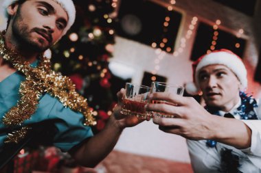 İki gülümseyen doktor ofisinde yılbaşı kutlamak. Santa Claus şapkalı adam. Ofiste Noel ağacı. Bilgisayar masasında. Beyaz ceketli adam. İçki içerken. Yeni yıl partisi. Meslektaşım ile kutlama.