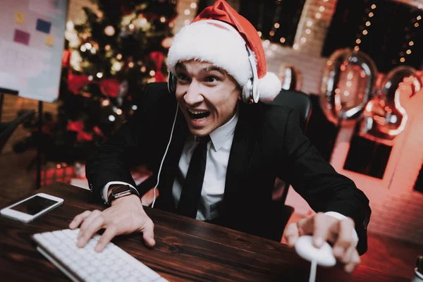 在新年前夕 生意人在电脑上玩 在办公室的圣诞树 书桌上的笔记本电脑 业务理念 穿黑色西装的男人庆祝新年 使用数字设备 — 图库照片