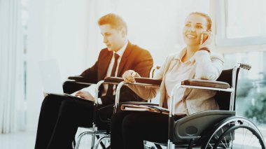 Kişi tekerlekli sandalyede. Kadın devre dışı. Panoramik görünümü. Beyaz iç. İnsanlar sınırlı olanakları ile. İş görüşmesi. İş elbiseleri. İş gezisi. Kadın tekerlekli sandalye konuşuyor. Adam tekerlekli sandalyeye mahkum.