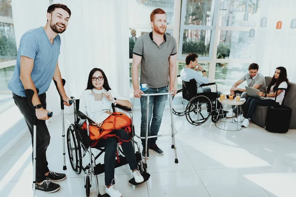 People in a Wheelchair. Disabled in the Hall. Woman in a Wheelchair. The man on crutches. Room with panoramic view. Gray sofa. White interior. Meeting Friends with Disabilities. Limited Opportunities.