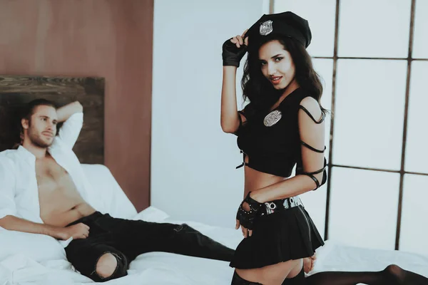 ブルネットの少女 セクシーな警官衣装の女性 ベッドの上の銃を持つ少女 白いリネン 警察キャップの女性 セックス ゲーム 寝室に男 セクシーなマン少女銃と Handcuffst — ストック写真