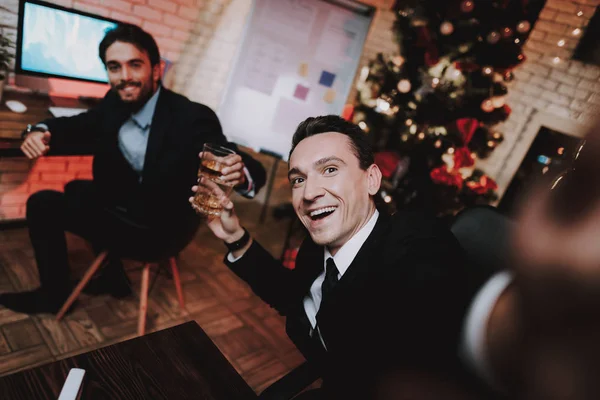 生意人使用智能手机在除夕夜 在办公室的圣诞树 书桌上的笔记本电脑 业务理念 穿黑色西装的男人庆祝新年 使用数字设备 拍摄自拍 — 图库照片