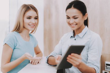 Resepsiyonist Tablet gösterir. Kadın resepsiyonist. Resepsiyon işyeri. Güzellik Salonu işyerinde. Beyaz iç. Esmer alımı işçi. Güzellik Consept. Gülümseyen Salon çalışan. Müşteri kaydı.