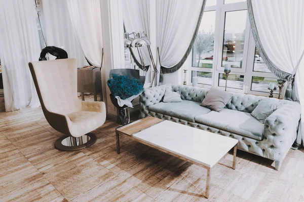 Fashion Workplace. Blue Sofa and Big Window. Fashion Salon. Luxury Design. White Interior in Salon. Mirror Decor. White Chandelier in Room. Room with White Interior. Large Room in Beauty Salon.