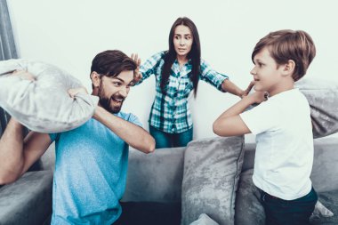 Aile yastık ile mücadele ve evde eğlenin. Baba ve oğul. Üzgün anne. Kapalı iyi eğlenceler. Ebeveynlik kavramı. Yastık kavgası. Tıraşsız genç adam aile evde. Mutlu bir aile.