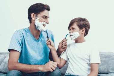 Baba ve oğul birlikte evde tıraş gülümseyerek. Baba ve oğul. Gülümseyen insanlar. Ebeveynlik kavramı. Evde aile. Tıraş adam sağlık ve hijyen kavramı. Küçük çocuk. Ustura ile adam.