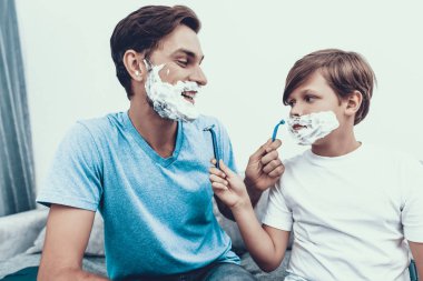 Baba ve oğul birlikte evde tıraş gülümseyerek. Baba ve oğul. Gülümseyen insanlar. Ebeveynlik kavramı. Evde aile. Tıraş adam sağlık ve hijyen kavramı. Küçük çocuk. Ustura ile adam.