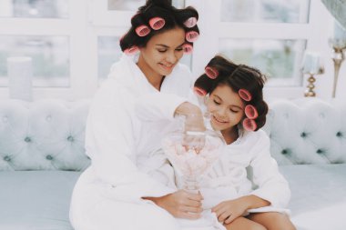 Curlers ile küçük hanım. Anne ve kızı Spa. Consept güzellik salonu. Kız ve tatlılar yemek anne. Kadın ve mutlu bir çocuk. Curlers kadınla. Güzellik Salonu tatlılar. Spa salonda mavi kanepe.