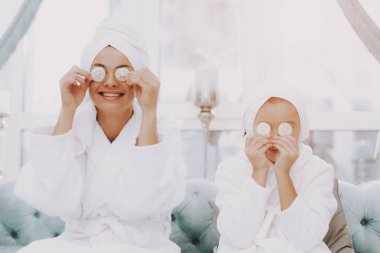 Güzellik Salonu gülümseyen insanlar. Anne ve kızı Spa. Consept güzellik salonu. Güzel yüzüm. Kadın ve mutlu bir çocuk. Curlers kadınla. Selfie yapıyor. Mavi koltuk Spa salonda. Beyaz iç.