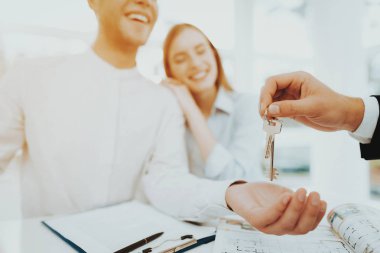 Genç çift Rieltors anahtarında üzerinde eller bakıyorum. Parlak Office. Anahtarları bir el. Bir emlak alımı. Panoramik pencerelere. İş görüşmesi. Müşteri ve alıcı. Tartışma sunuyoruz. Profesyonel sözleşme.