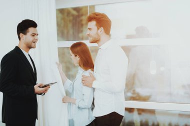 Profesyonel Rieltor genç çift için bir özellik gösterir. Bir sözleşme yaparak. Tablet hakkında bilgi. Panoramik pencerelere. İş görüşmesi. Müşteri ve alıcı. Tartışma sunuyoruz. Profesyonel sözleşme.