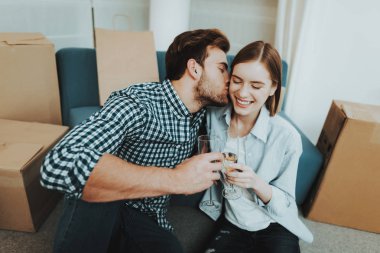 Genç çift yeni apartmanda. Şampanya kutlama. Birbirimizi seviyoruz. Neşeli şekerler. Yeni bir hayat. Kişisel düz. Mutlu bir aile. Aile içi yaşam. Turuncu kutu. Yere siting.
