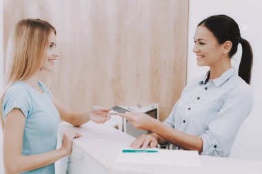 Kadın resepsiyonist. Salonda kartvizit. Güzellik Salonu işyerinde. Beyaz iç. Beyaz resepsiyon masası. Güzellik Consept. Gülümseyen Salon çalışan. Müşteri kaydı. Çalışan istemci konuşuyor.