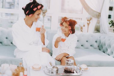 Çay Spa salonda. Anne ve kızı Spa. Consept güzellik salonu. Güzel küçük hanım. Güzel yüzüm. Kadın ve mutlu bir çocuk. Curlers kadınla. Gülümseyen kişi. Spa salonda mavi kanepe.