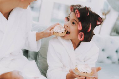 Curlers olan küçük kız. Kek yeme. Anne ve kızı Spa. Kız ve anne ile pasta. Güzel küçük hanım. Güzel yüzüm. Kadın ve mutlu bir çocuk. Curlers kadınla. Spa salonda mavi kanepe.