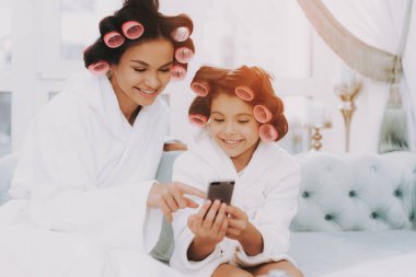 Curlers ile küçük hanım. Anne ve kızı Spa. Consept güzellik salonu. Güzel küçük hanım. Güzel yüzüm. Kadın ve mutlu bir çocuk. Anne ve kızı telefona bak. Spa salonda mavi kanepe.