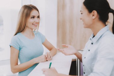 Kadın resepsiyonist. Resepsiyon işyeri. Güzellik Salonu işyerinde. Beyaz iç. Beyaz resepsiyon masası. Güzellik Consept. Gülümseyen Salon çalışan. Müşteri kaydı. Resepsiyonist telefon görünüyor.