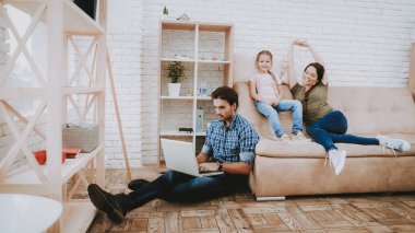 Mutlu bir aile. Anne ve kızı. Aile birlikte dinlenme. Mutlu çocuk ve anne. Kahverengi kanepe dairede. Dizüstü bilgisayar üzerinde çalışıyor. Laptop olan adam. Gülümseyen aile dinlenme. Anne kız dinlenme ile.