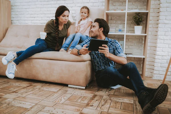 幸福的家庭 父母和女儿 一家人在一起休息 快乐的孩子和父母 公寓里有褐色沙发 男子显示黑色平板电脑 微笑的家庭休息 妈妈和女孩休息 快乐假期 — 图库照片