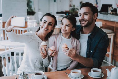 Gülümseyen insanlar. Genç aile. Selfei. Mutlu birlikte. İyi bir ilişki. Cafe. Aile tatili. Çay saati. Anne. Baba ve kızı. Etkin boş zaman. Şirin ilişki. Kutlama. Tatlım. Nefis.