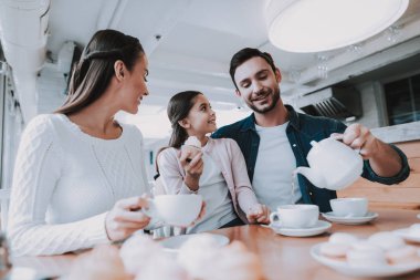 Genç aile. Çay saati. Cafe. Mutlu Together.Cupcake. Nefis. İyi bir ilişki. Aile tatili. Anne. Baba ve kızı. Etkin boş zaman. Şirin ilişki. Kutlama. Gülümseyen insanlar.