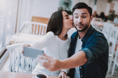 Selfei. İyi bir ilişki. Smartphone. Öpücük. Genç aile. Mutlu birlikte. Cafe. Aile tatili. Çay saati. Etkin boş zaman. Şirin ilişki. Kutlama. Tatlım. Nefis. Gülümseyen insanlar.