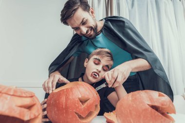 Adam ve küçük çocuk kostümleri kabak oyma. Yetişkin yakışıklı adam ve küçük Cadılar Bayramı kostümleri yapma Jack-o-fener birlikte giyen çocuk. Cadılar bayramı kutlaması. Ailesi ve çocukluk kavramı
