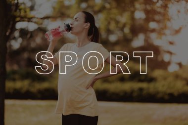 İç. Fitness Mat. Vuruş göbek. Gülümseyerek. Hamile. Kadın. Pembe tişört. Yürü. Park. Spor şişe. Güzel. İlgilenmek. CrossFit. Egzersiz. Mutluluk. Sağlıklı bir yaşam tarzı. Anne. Doğa. Spor giyim.