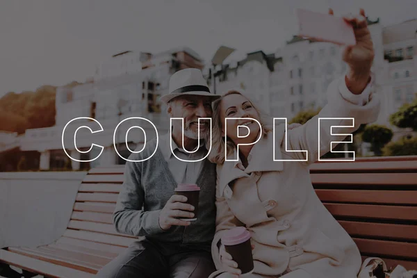 Old Couple. Smartphone. Selfie. Glass of Coffee. Two Pensioners. Have Fun. Happy Together. Bubbly Relationships. Love Story. Flowers. Alley in Park. Sit. Retired. Leisure Time. Smiling.