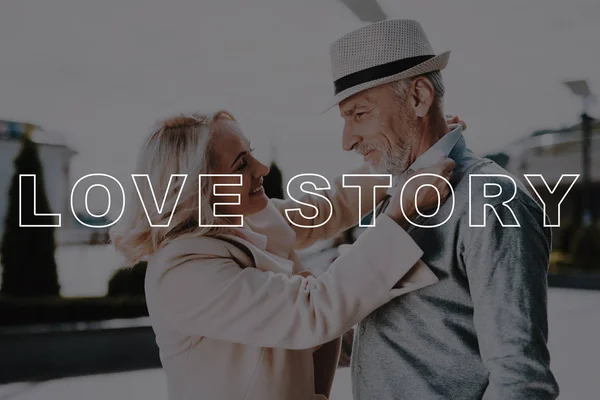 White Hat. Bubbly Relationships. Hugs. Happily. Elderly Man. Love Story. Alley in Park. Old Couple. Two Pensioners. Woman. Gift. Retired. Happy Together. Leisure Time. Have Fun. Smiling.