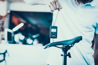 Adam taşınabilir elektronik ölçek spor dükkanında tutar. Tezgâhtar beyaz tişört içinde closeup ölçü ve bulanık artalanları Modern siyah eyer kamera ağırlık ayrıntılarını gösterir