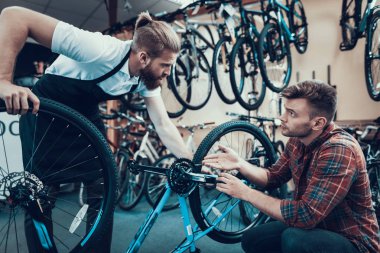 İki adam bisiklet spor atölye inceleyin. Cycle Store'a genç gülümseyen adam Modern Bisiklet tamir profesyonel tamirci yardımcı oldu. Bisiklet bakım ve spor salonu konsept