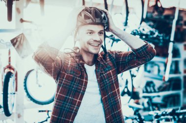 Kask bisiklet için yakışıklı mutlu adam denemede sürmek. Mutlu gülümseyen beyaz müşteri spor Bisiklet Mağazası bulanık artalanları ile Modern kask ölçme kırmızı kareli gömlek giyen portresi