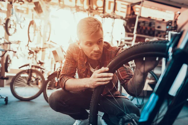 Closeup Man Examines Bicicleta Roda Oficina Retrato Jovem Caucasiano Vestindo — Fotografia de Stock