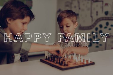 İki sıkılmış çocuklar bir masada oturan satranç oynamak. Ev boş. Çocuk tatil aktivitesi. Hafta sonu arkadaşım. Aile ilişkisi var. Bir hamle yapın. Mantıksal oyunu. Masanın üzerinde rakamlar. Akıllı çocuklar.