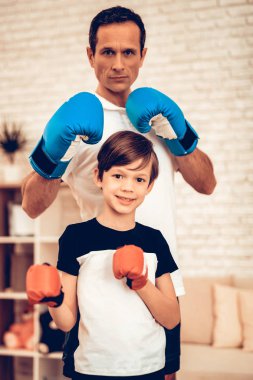 Boks rafa hazır. Kırmızı ve mavi. Evde spor. Yukarı üç aylık dönemde sıcak. Tablet elinde. Boks eldivenleri. Spor yapıyor. Dostum ve oğlum evde tren. Boks eldivenleri dairesinde çocuk. Küçük çocuk.