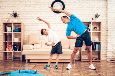Boy Standing on Scales. Father and Son do Spotting. Sport at Home. Warm Up in Quarter. Lying on Gymnastic Mat. Dumbbells in Hands. Boxing Gloves. Doing Sports. Man and Boy Train at Home. Swing Press. clipart