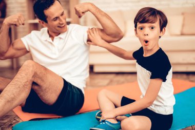 Adam gösteren çocuk kasları. Evde spor. Yukarı üç aylık dönemde sıcak. Spor salonu mindere yalan. Spor yapıyor. Adam tren evde. Sağlık kavramı. Sağlıklı bir yaşam tarzı. Kat jimnastik mindere oturmuş. Çocukla Trainer.