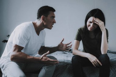Evli çift gri yatak üzerinde oturan ve savunarak. Hayal kırıklığına karısı çatışma evimde kavga sırasında ağlıyor, öfkeli koca çığlıklar portresi. Aile ilişki sorunları.