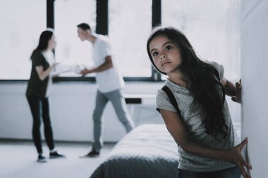 Koyu saçlı kız anne evde savunarak dinler. Çocuk portresi duvar ise anne ve baba azarı kasvetli yaslanmış oturma odasında görünüyor. Aile ilişki sorunları kavramı