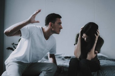 Kadın ve erkek savaşır yatağa evde otururken. Evli çift portre üzerinde gri kareli oturan ve savunarak. Kızgın karı koca yatak odamda çakışma var. Aile ilişki sorunları kavramı