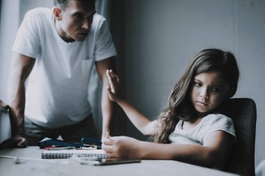 Küçük kız oturuyor masada baba savunan tamamlayın. Koyu saçlı sevimli çocuk portresi döner T-Shirt giyen adamdan uzak ev ödevi içinde not etmek. Aile çatışma kavramı