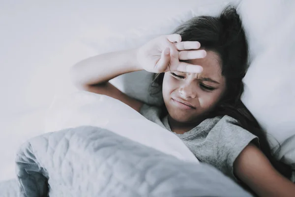 女孩起床 遮住眼睛从明亮的光 特写肖像的可爱的黑发白种白人孩子穿灰色 恤保持双手额头躺在白色的床上 清晨觉醒概念 — 图库照片